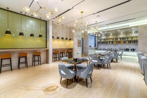 A modern restaurant with a bar area, seating arrangements, and a display of bottles. - Echarm Hotel (Kunming)