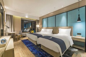 A hotel room with a large bed, bedside tables, a desk, and a seating area. - Echarm Hotel (Kunming)