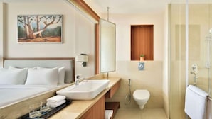 A hotel room with a bed, a bathroom with a shower, and a painting on the wall. - Grandville Hotel Pousada (Barra de São Miguel)