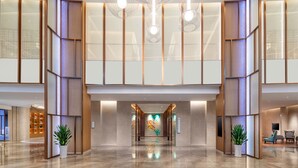Eine geräumige Lobby mit poliertem Marmorboden, einer zentralen Kunstinstallation und Sitzbereichen.
