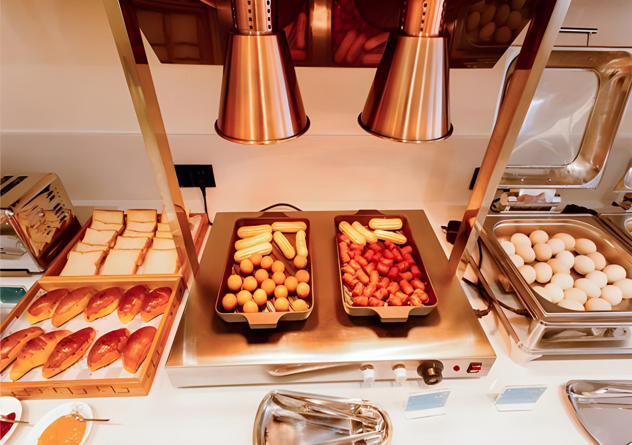 A buffet setup with various food items including bread, pastries, and eggs.