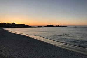 A beach with a calm sea, a clear sky, and a distant shoreline with buildings. - Villa in Monticello with swimming pool (MONTICELLO)