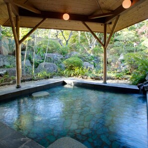 A stone-lined pool with a wooden pergola overhead, surrounded by rocks and greenery. - Shimoda Rendaiji Onsen Seiryuso (Shimoda)