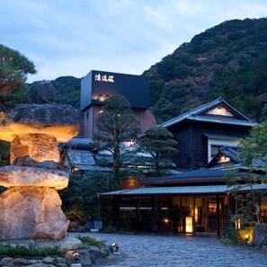 A traditional Japanese building with a modern extension, surrounded by natural rock formations and trees. - Shimoda Rendaiji Onsen Seiryuso (Shimoda)