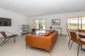 A spacious living area with a sofa, chairs, a dining table, and a TV mounted on the wall. - Villa in Monticello with swimming pool (MONTICELLO)