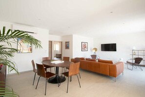 A modern living room with a sofa, TV, and dining area with chairs and a table. - Villa in Monticello with swimming pool (MONTICELLO)