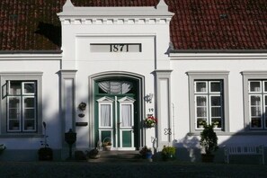 Ein Gebäude mit einer grünen Tür, weißen Wänden und der Hausnummer 1871.