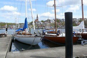 A marina with boats docked, a pier, and a church in the background. - Holiday apartment with 1 bedroom (Glücksburg- Schausende)