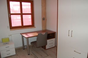 Ein Zimmer mit einem Holztisch, einem Stuhl, einer Heizung und einem Kleiderschrank.