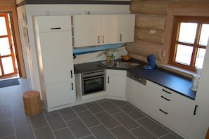 Eine kleine Küche mit weißen Schränken, einem eingebauten Backofen, einer Spüle und einem Fenster.