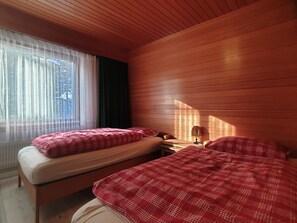 A room with two beds, a window with sheer curtains, and a wooden ceiling. - L'Orée 12 Appartement/Fewo 4-Bettwohnung by Interhome (Saas-Fee)