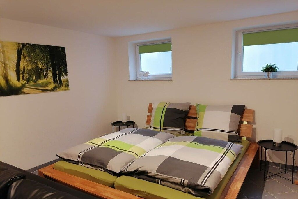 Ein Schlafzimmer mit einem Bett, zwei Nachttischen, einem Fenster und einem Bild an der Wand.