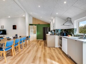 A modern kitchen with a dining area, wooden flooring, and a green accent wall. - "Nahuel" - 300m to the fjord by Interhome (Vinderup)