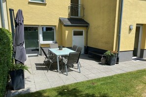 An outdoor patio with a table and chairs, a covered bench, and potted plants. - Holiday home Moseltraum (Dieblich)