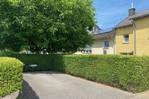 Une allée pavée mène à un bâtiment jaune sur lequel est installé un panneau solaire sur le toit.
