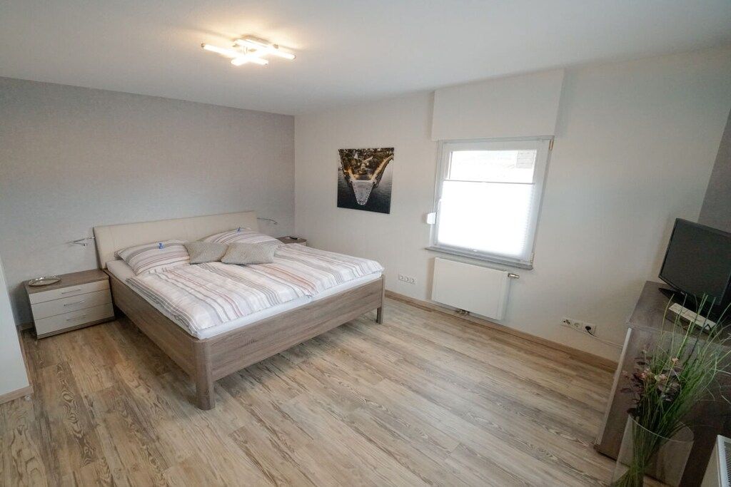 Una camera da letto con un letto, un comodino, una finestra e una televisione.