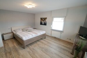 Une chambre à coucher avec un lit, une table de chevet, une fenêtre et un téléviseur.