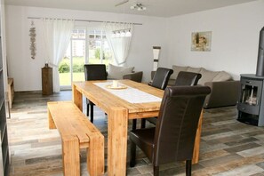A dining area with a wooden table and benches, a sofa, and a fireplace. - Stork's Nest House (1) (Dranske \/ OT lancken)