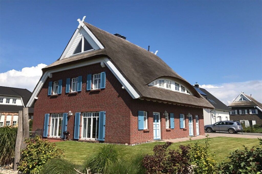 Une maison en briques rouges avec des volets bleus, un toit en pente et une cheminée bien visible.