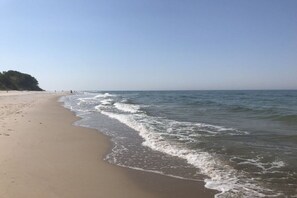 Ein Strand mit sandigem Ufer und sanften Wellen.