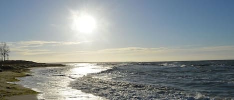 Ein Strand mit Wellen, blauem Himmel und strahlender Sonne.
