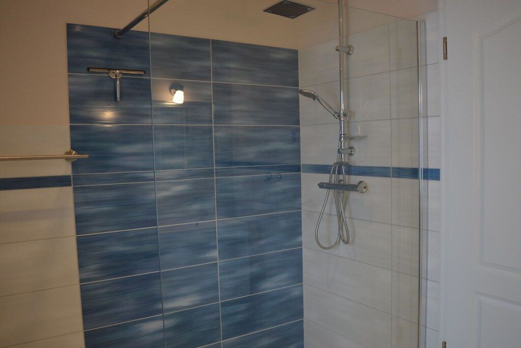 Eine Dusche mit Glastür, Duschbrause und fest installierter Bedienkonsole.