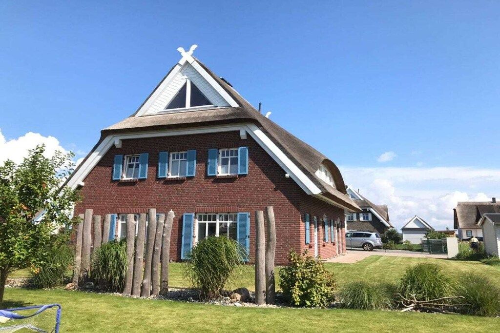 Ein zweistöckiges Haus mit einem geneigten Dach, einer Ziegelaußenwand und blauen Fensterläden.
