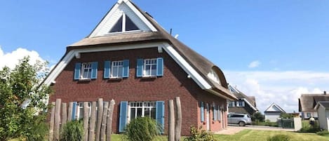 A two-story house with a sloped roof, a brick facade, and blue shutters.