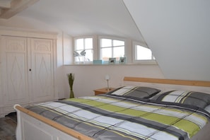 Ein Schlafzimmer mit einem Bett, einem Nachttisch, einem Fenster mit Blick und einem Kleiderschrank.