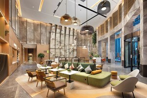 Un vestíbulo amplio con techo alto, paredes de mármol y diversas opciones de asientos, incluyendo sofás y sillones.