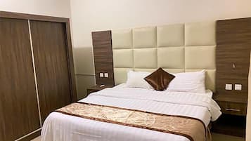 A hotel room with a large bed, a wardrobe, and a nightstand.