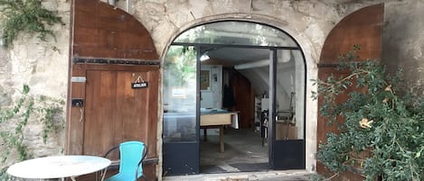 An entrance to a building with a wooden door labeled 'ATELIER' and an open doorway leading inside.