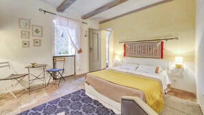 A bedroom with a bed, a chair, a table, and a window. - Characterful Guest Room with Historic Charm in Fons-sur-Lussan (Fons-sur-Lussan)