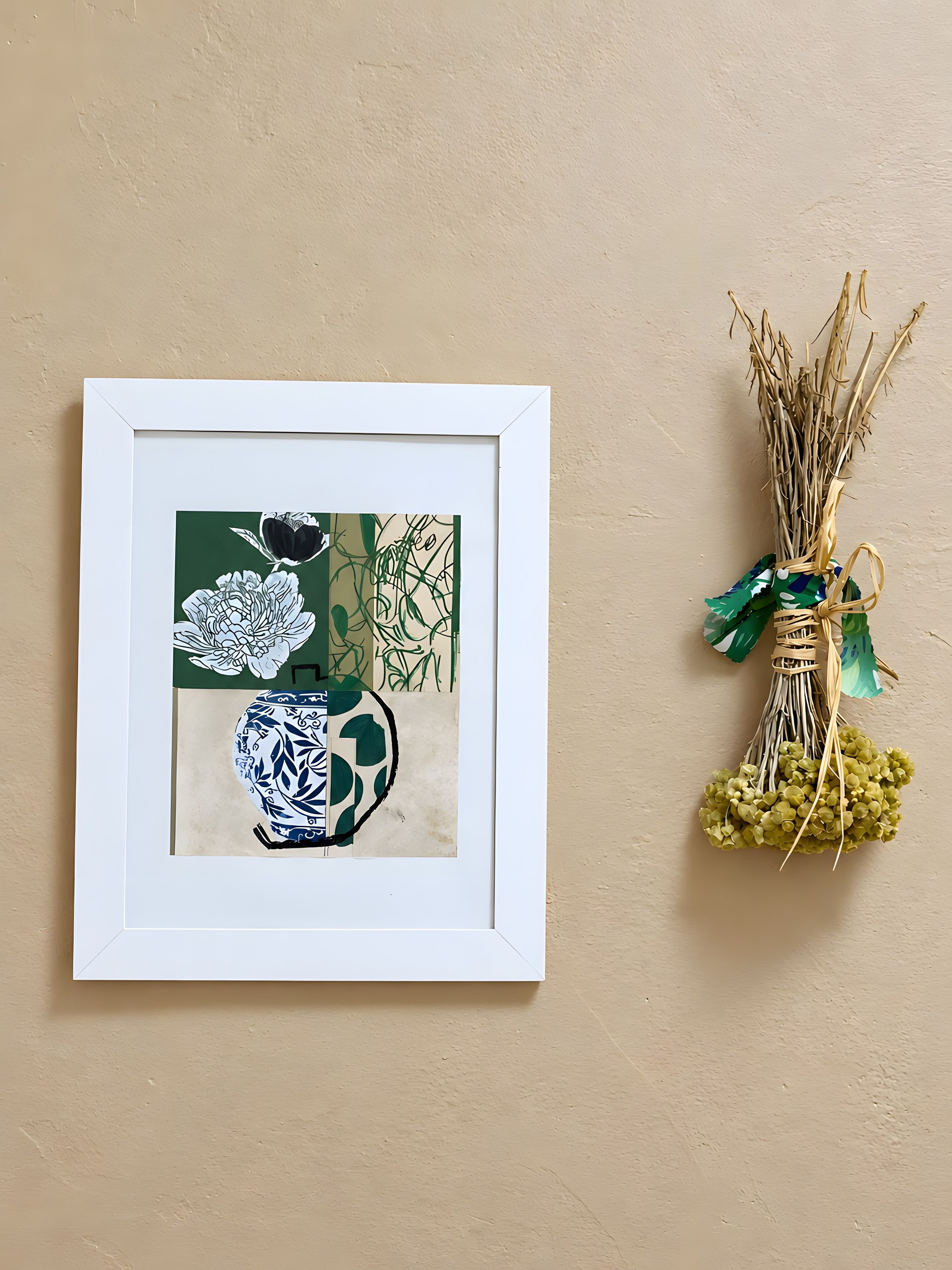 A framed artwork with floral designs and a vase, alongside a decorative plant arrangement on a wall.