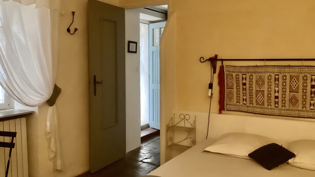 A room with a bed, a window with curtains, a door, and a wall-mounted lamp. - Characterful Guest Room with Historic Charm in Fons-sur-Lussan (Fons-sur-Lussan)