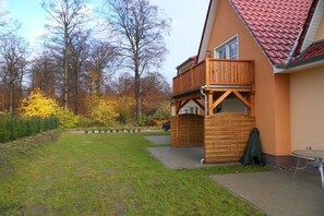 A two-story house with a wooden deck and a red-tiled roof. - Holiday apartment with 2 bedrooms (Kölpinsee)