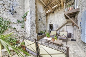 Un intérieur rustique en pierre, agrémenté d’un portail en fer forgé, d’un escalier et de plantes en pot.