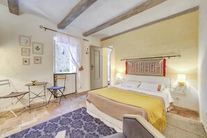 Ein Schlafzimmer mit einem Bett, einem Sessel, einem Tisch und einem Fenster.