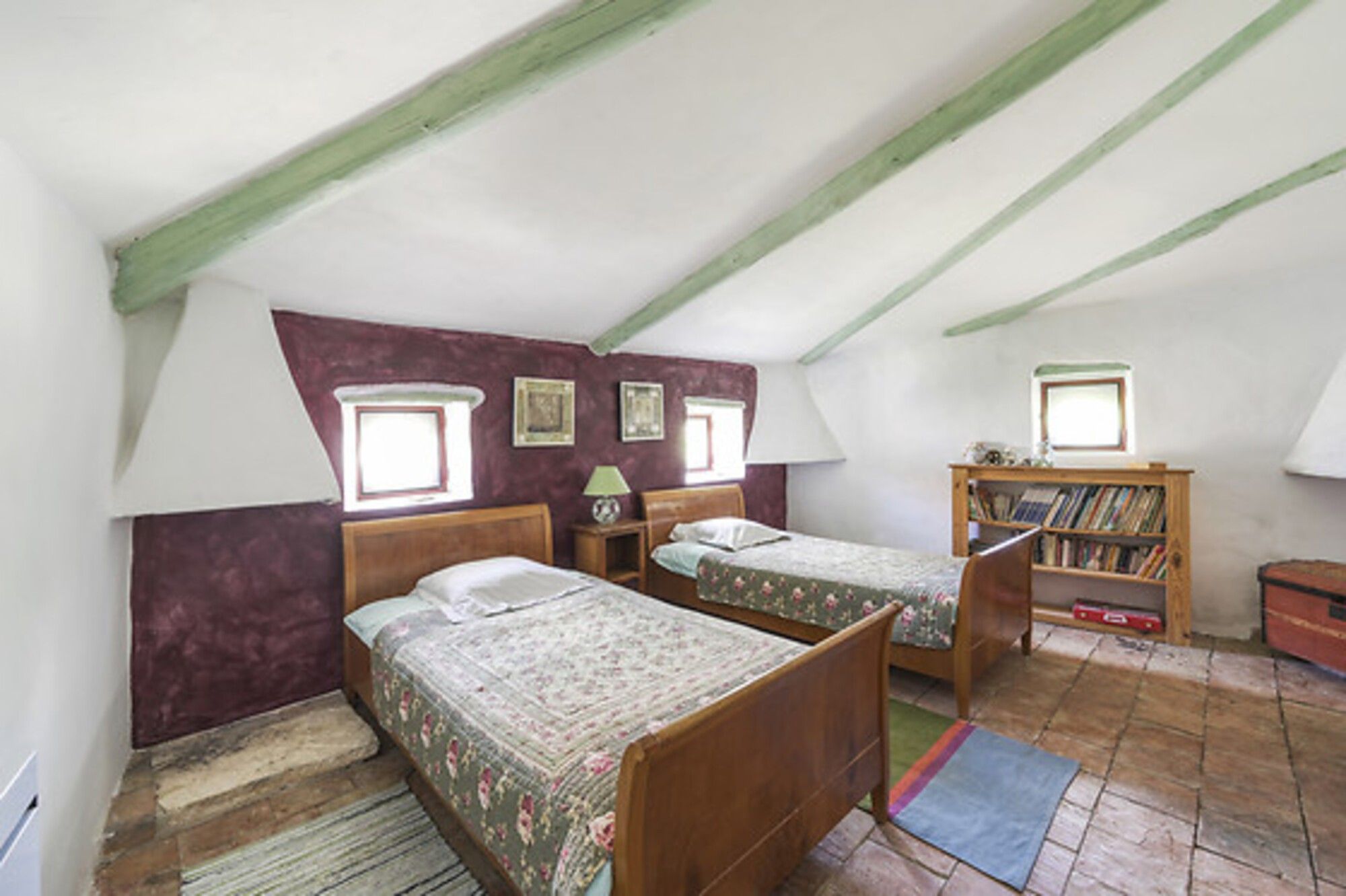 Une chambre à coucher avec deux lits en bois, une bibliothèque et une fenêtre.