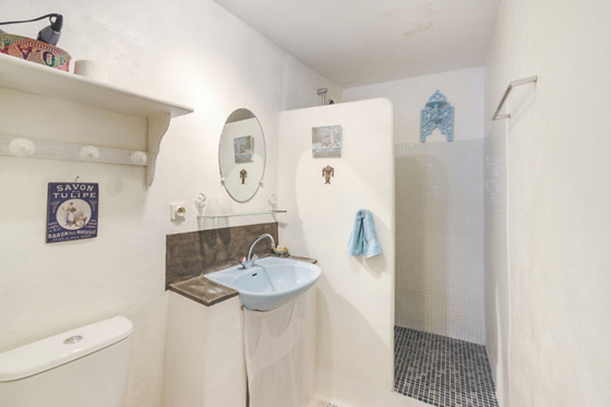 Ein Badezimmer mit Toilette, Waschbecken, Spiegel, Dusche und einem Handtuch, das an der Wand hängt.