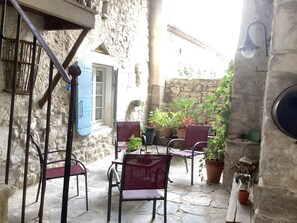 Eine Terrasse mit Steinboden, Sitzgelegenheiten, Kübelpflanzen und einer rustikalen Steinmauer.