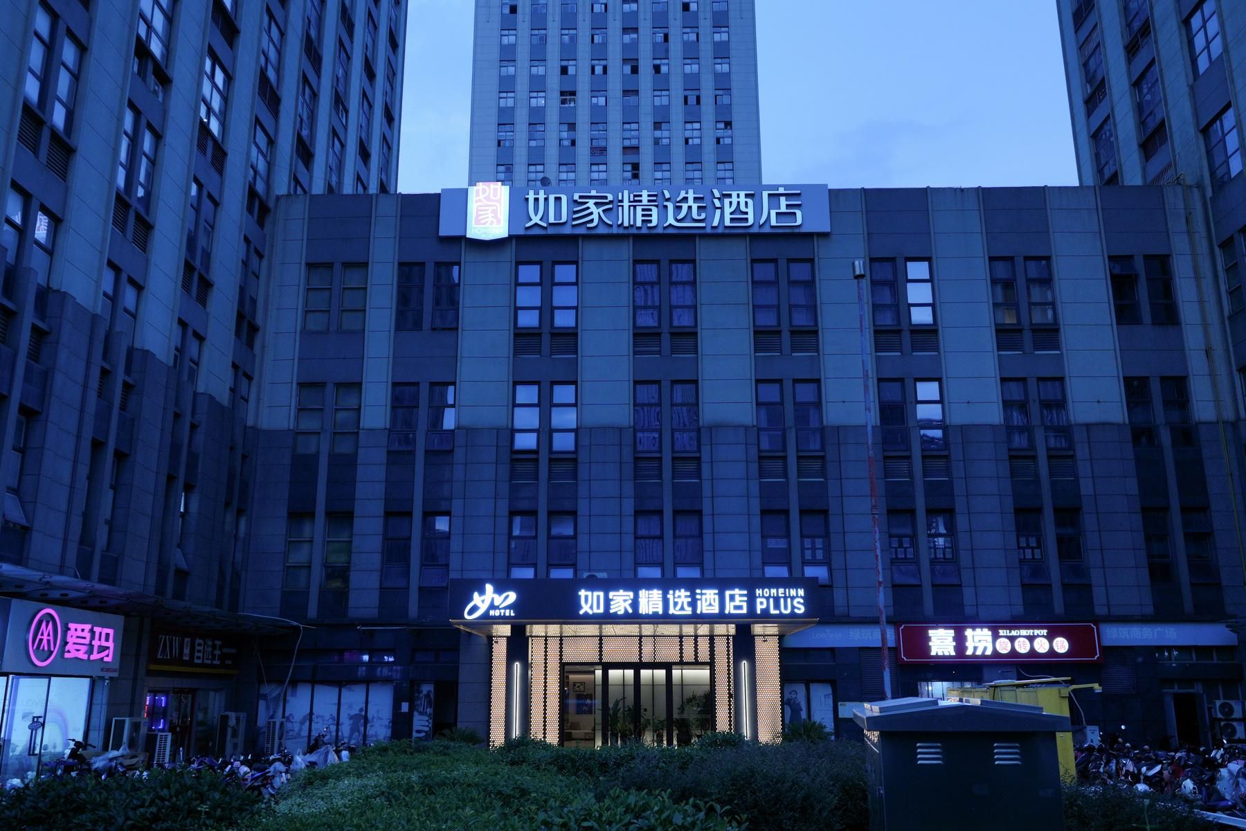 A hotel building with a prominent sign for 'Homeinn Plus' and a smaller sign for 'Xilad Hot Pot' restaurant.