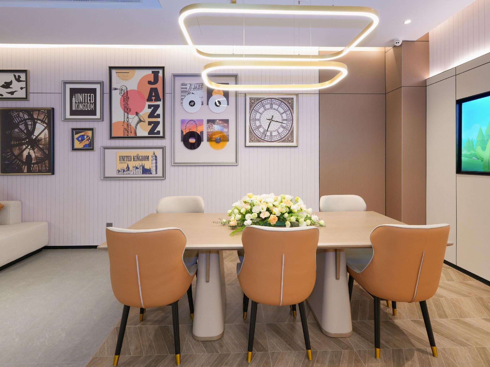 A modern dining area with a long table, four chairs, and a floral centerpiece.