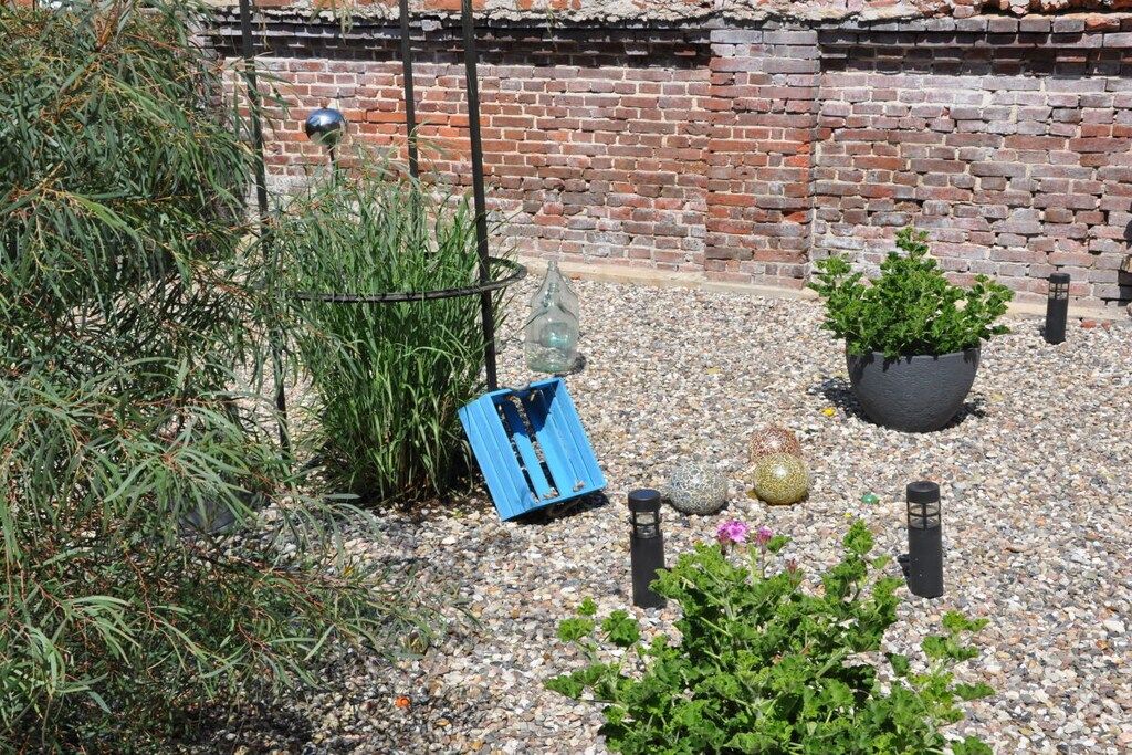 A garden with a brick wall, potted plants, and a blue structure.