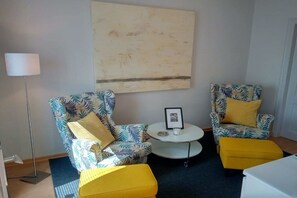 A room with two patterned armchairs, a small round table, and a floor lamp. - Holiday home with 1 bedroom (Stadt Fehmarn OT Burg)