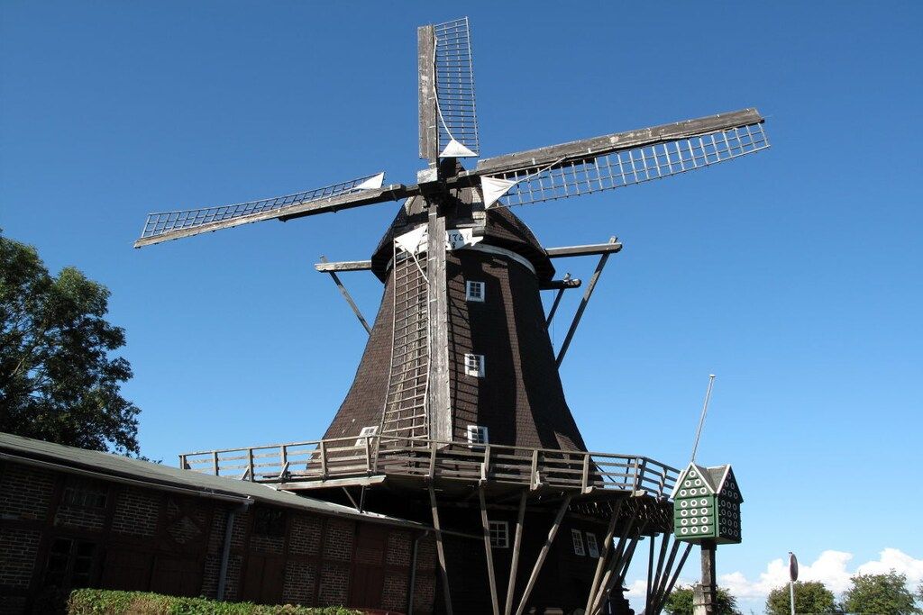 A traditional windmill with a wooden structure and a metal lattice windmill.