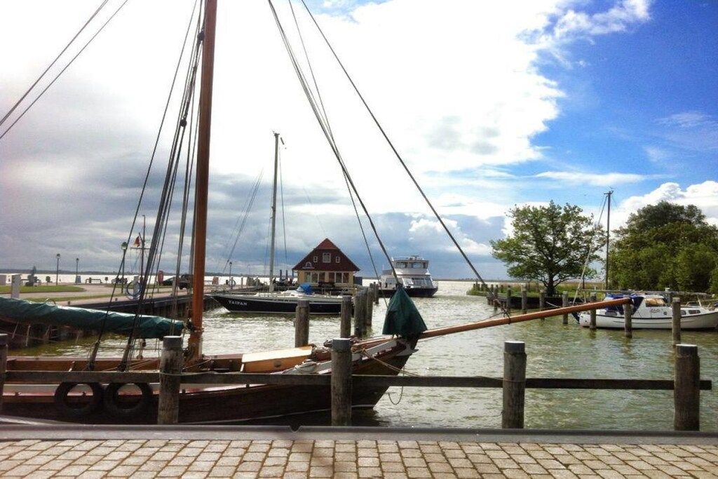 Un puerto deportivo con barcos amarrados, un muelle de madera y un edificio con techo rojo al fondo.