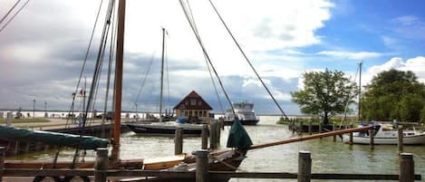 Un puerto deportivo con barcos amarrados, un muelle de madera y un edificio con techo rojo al fondo.