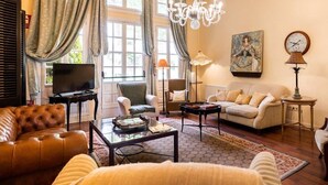 Una sala de estar con un sofá de cuero, una mesa de centro, un televisor y una araña.