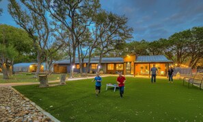 A residential area with a house and a covered structure, surrounded by trees and a well-maintained lawn. - Terracotta Haven Hot Tub Pool Games Sleeps26 (Wimberley)